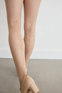 Back view of the legs in the Back Vine Sheer Tights in Dune, showing the vine pattern running up the back leg, styled with heels.