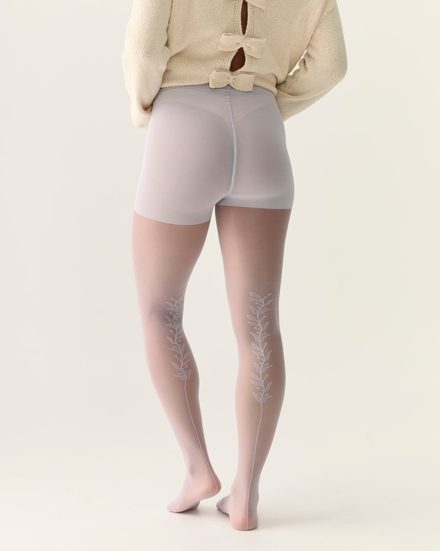 Person wearing sheer tights with a back vine floral embroidery in lilac