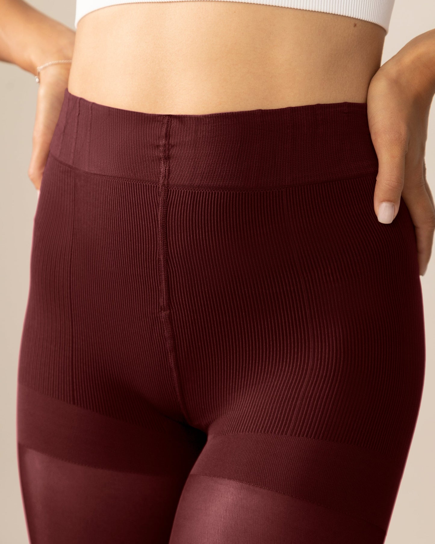Burgundy shapewear tights worn by a person on a beige background