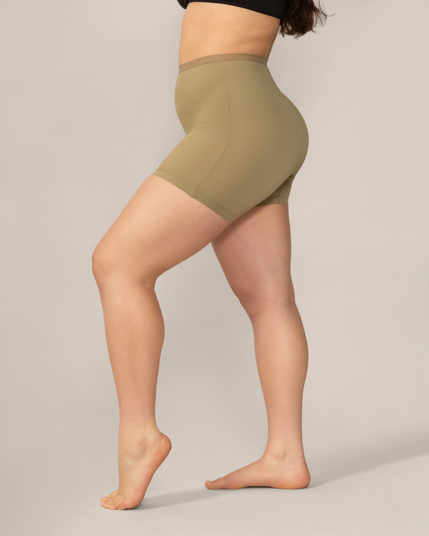 Person wearing olive green anti chaffing shorts on a plain background